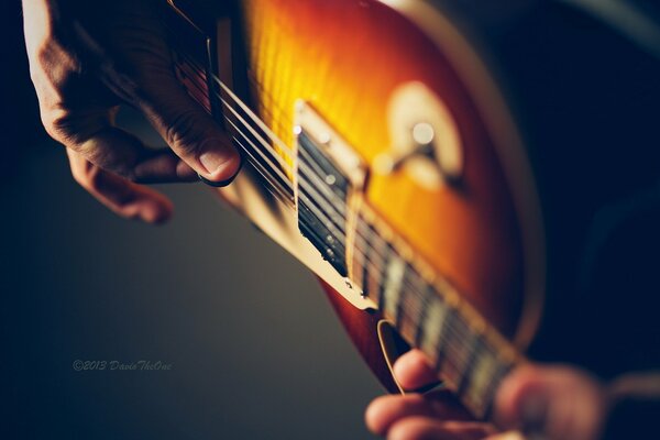 Palmas de los hombres en el diapasón de la guitarra