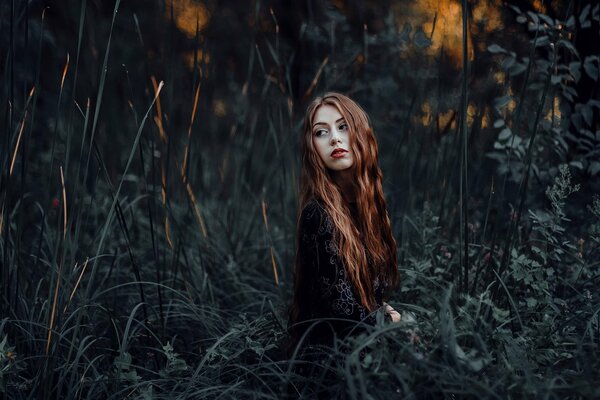 Pelirroja chica en el fondo de la naturaleza oscura