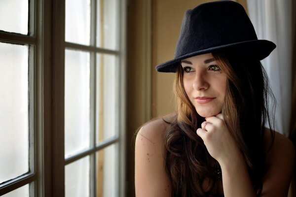 La ragazza con il cappello guarda fuori dalla finestra