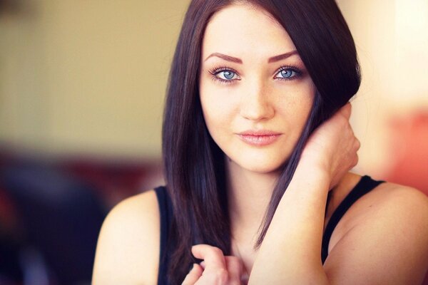 A girl with blue eyes holds her hair with her hand