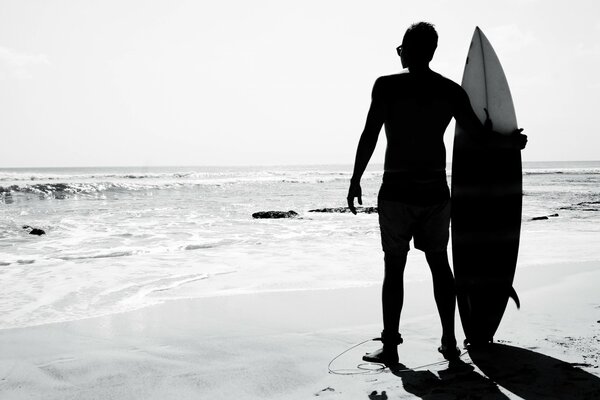 Hombre surfista parado junto al océano