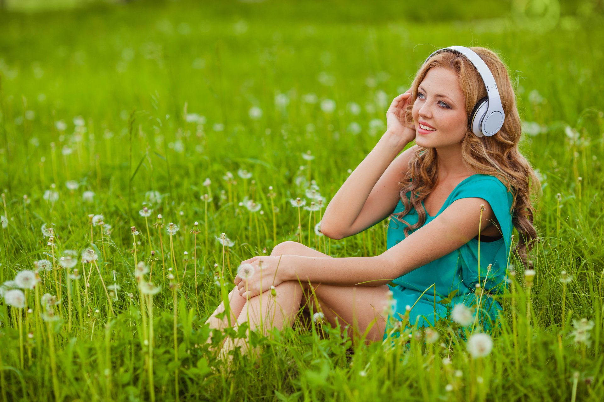 ragazza bionda erba denti di leone fiori paraorecchie sorriso