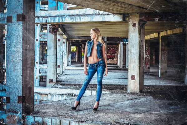 A girl with a beautiful figure poses at a construction site