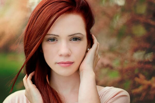 Portrait of a red-haired beauty on the background of autumn