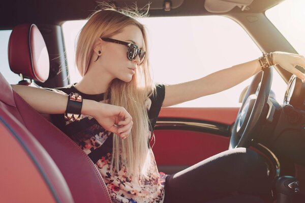 Chica rubia se sienta al volante de un coche