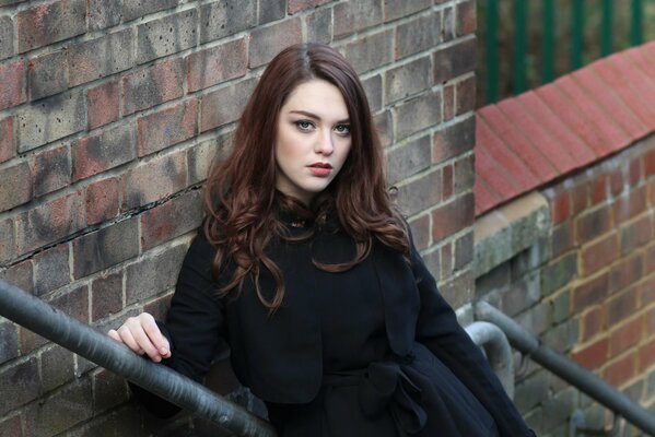 Brunette in a black coat on the stairs