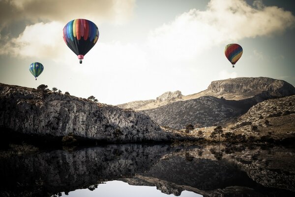 Paisaje de globos deportivos flotando sobre un lago de montaña