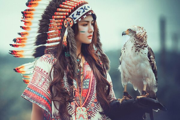 Una chica con un halcón y un tocado de plumas