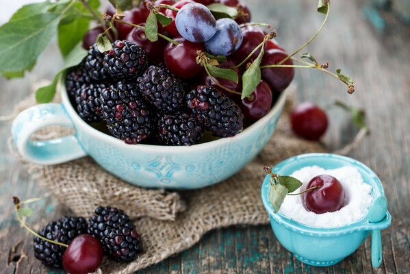 Blackberries plums and cherries in a blue plate