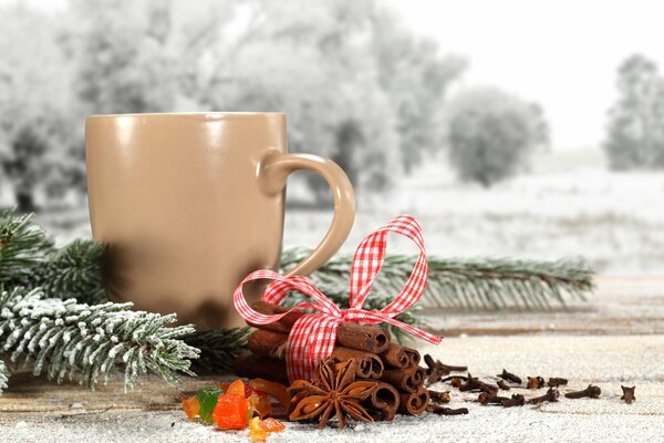 Cinnamon sticks next to a mug and a fir branch