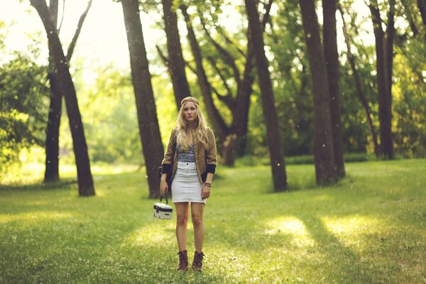 Chica rubia de pie en el bosque