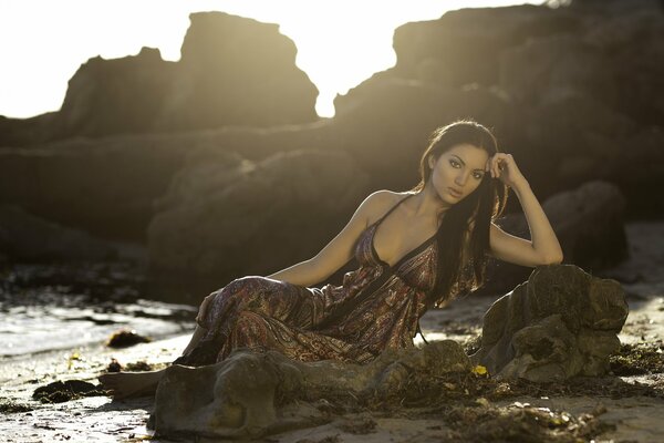 Chica en un vestido en la costa de la piedra