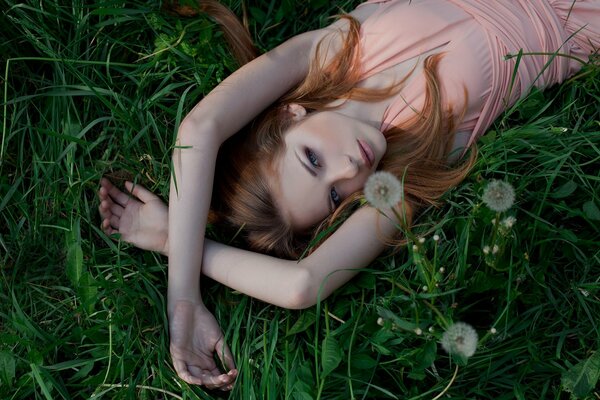 A pretty woman in a dress is lying on the grass