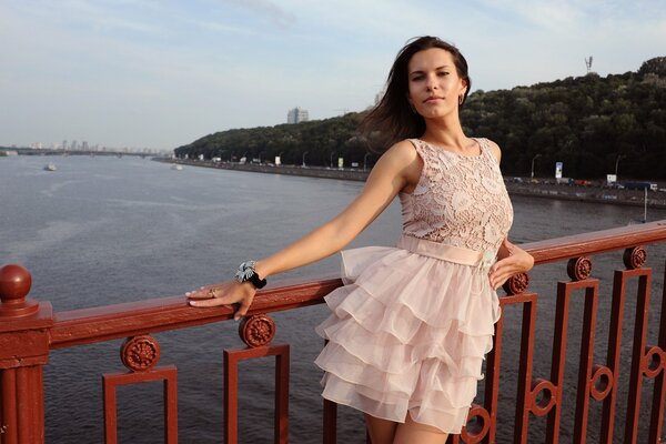 Mädchen im rosa Kleid posiert auf der Brücke