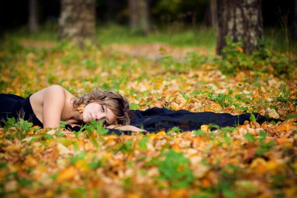 Ragazza che giace nel fogliame nella foresta d autunno