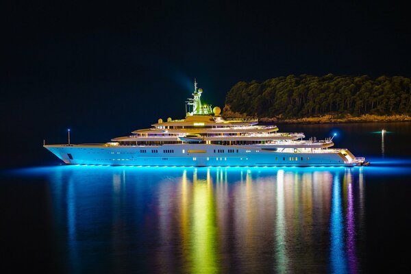 Luxury yacht sails past the island in the night