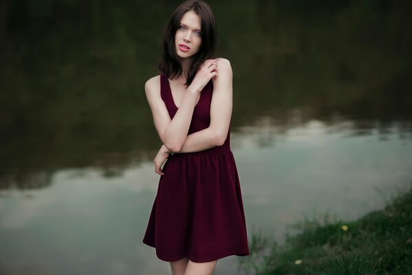 A girl by the river in a red dress