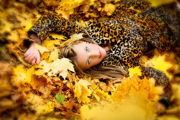 Ragazza in abito leopardo sul fogliame autunnale