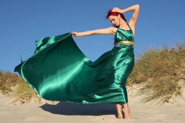 Chica posando en la arena. Vestido verde tren