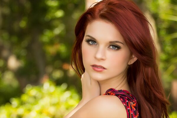 Cute red-haired girl looks with her blue eyes