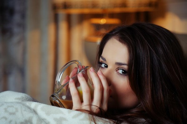 The brunette drinks tea from a mug