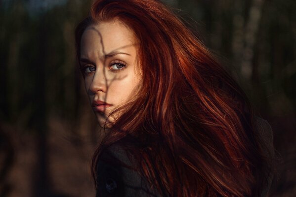 Red-haired girl with a shadow on her face from a tree branch