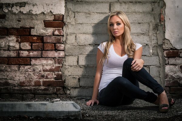 Rubia sentada en una pared de piedra