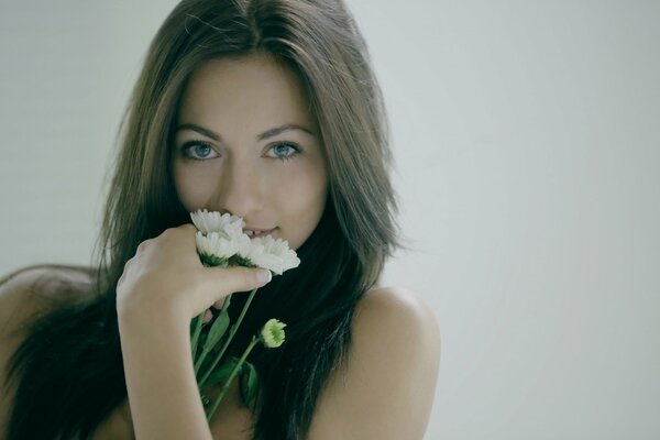 Mädchen mit schönen blauen Augen hält einen Blumenstrauß aus Gänseblümchen