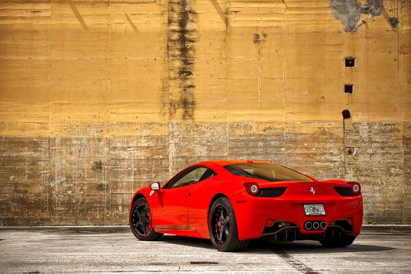 Red ferrari 458 italia on the background of an old yellow wall
