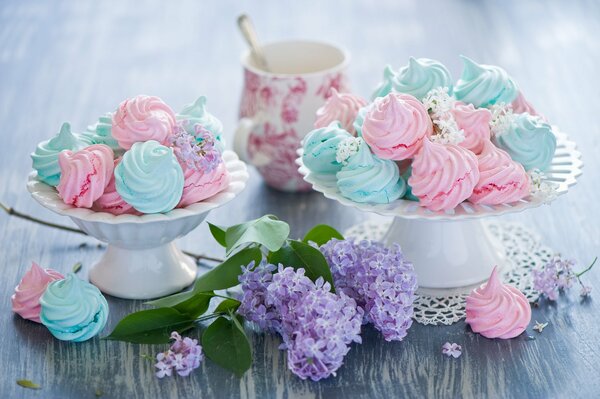 Pink and blue meringue in vases near a branch of lilac