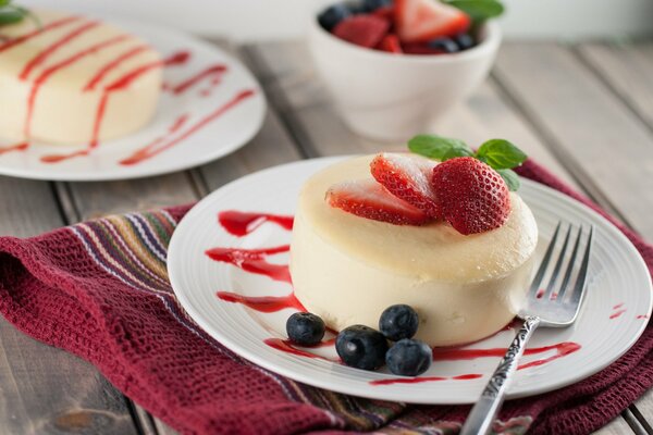 Round dessert on a plate with strawberries and blueberries