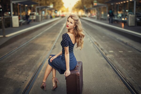 Fille assise sur une valise rétro