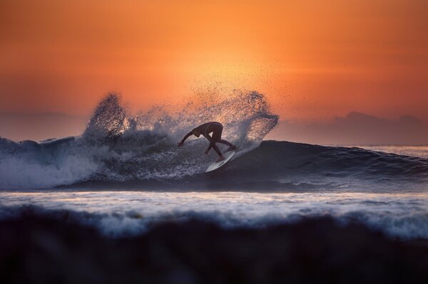 Surfer conquers the waves at sunset