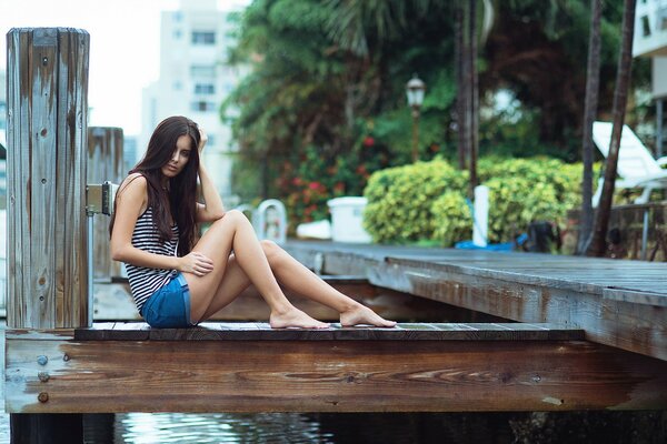 Chica en pantalones cortos sentado junto al río