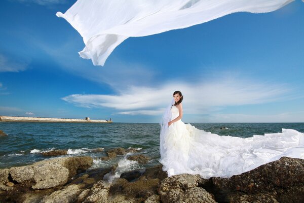 Ragazza in abito da sposa in riva al mare