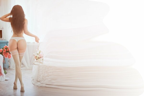 Fille en bas avec de longues jambes, beau cul et culotte, tenant un bouquet de fleurs