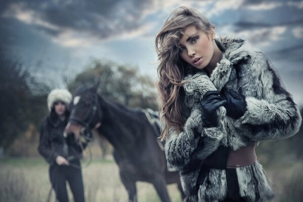 Fille en manteau de fourrure posant sur fond de cheval