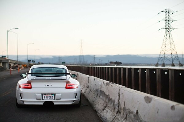 A white Porsche is driving on the road