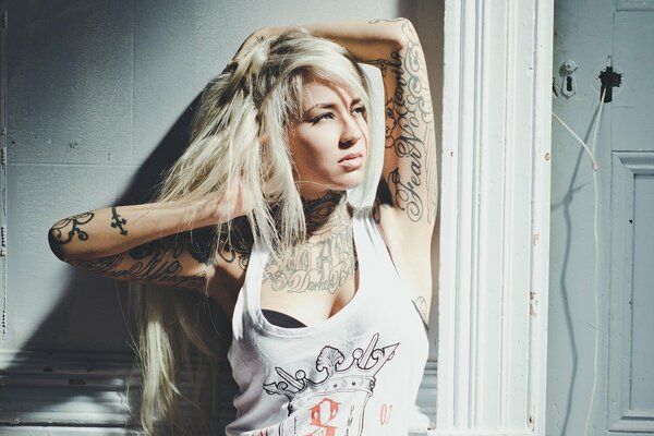 Fille blonde en maillot blanc avec tatouage