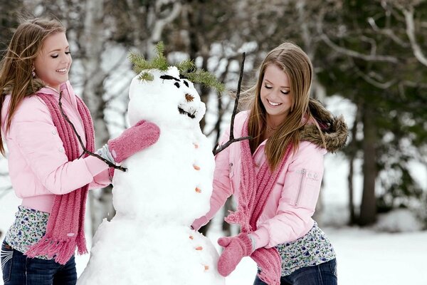 Twins in mittens make a snowman