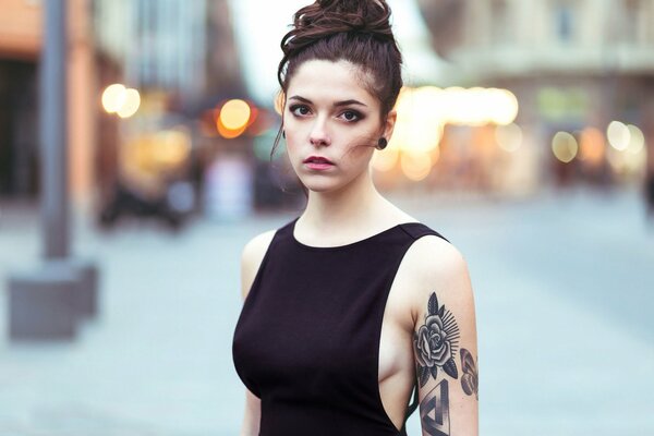 Fille avec un faisceau dans un t-shirt noir et avec un tatouage de rose