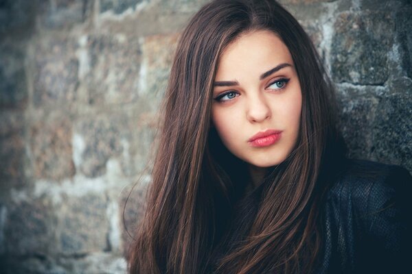 Morena de ojos azules Mira hacia un lado contra la pared de fondo