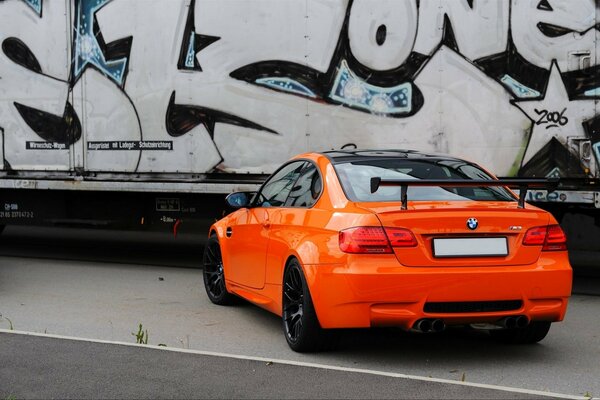 Helles Auto in orange Farbe auf Wandhintergrund mit Graffiti