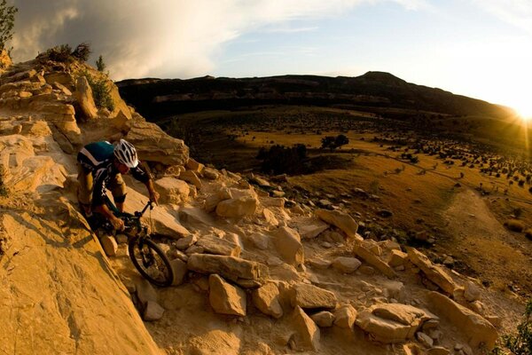 A cyclist in a helmet rides through a canyon