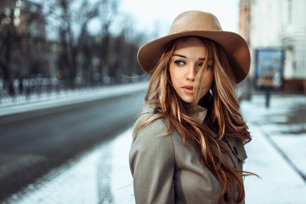 A girl in a hat on the background of the road