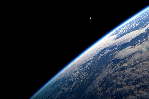 The moon is visible from behind the Earth in space