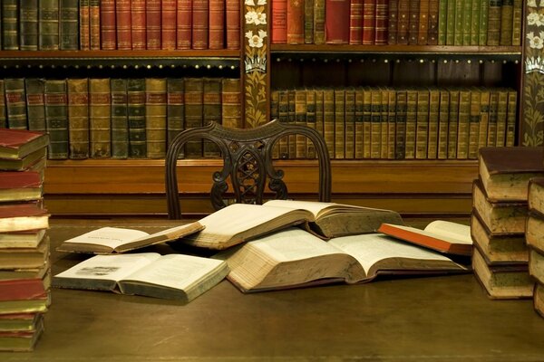 Library. An open book on the table. Shelves with books. Literary living room