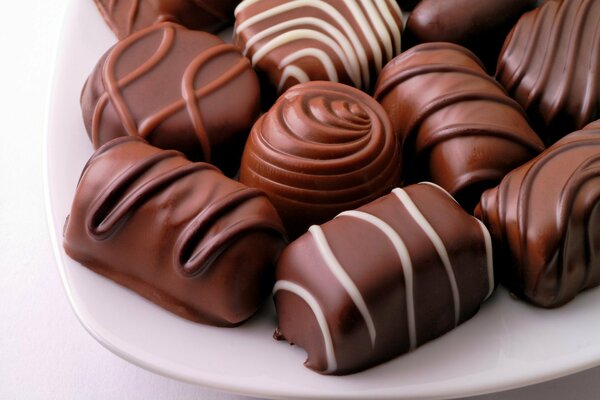 Plaque avec des bonbons au chocolat sur fond blanc