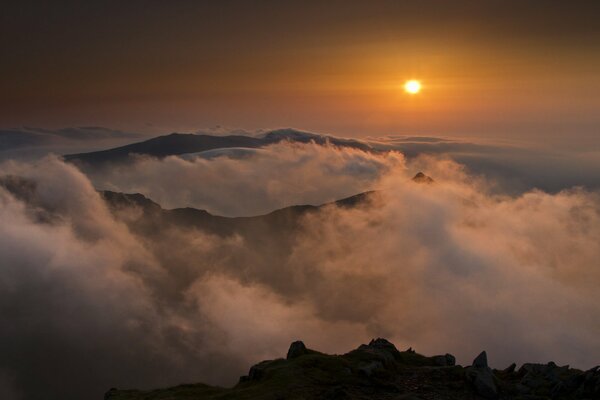 The setting sun over the mountains and fog