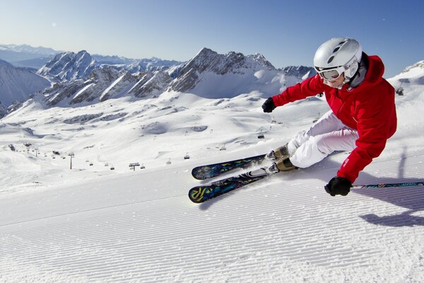 The mountains are blue sky , a woman is riding on skis